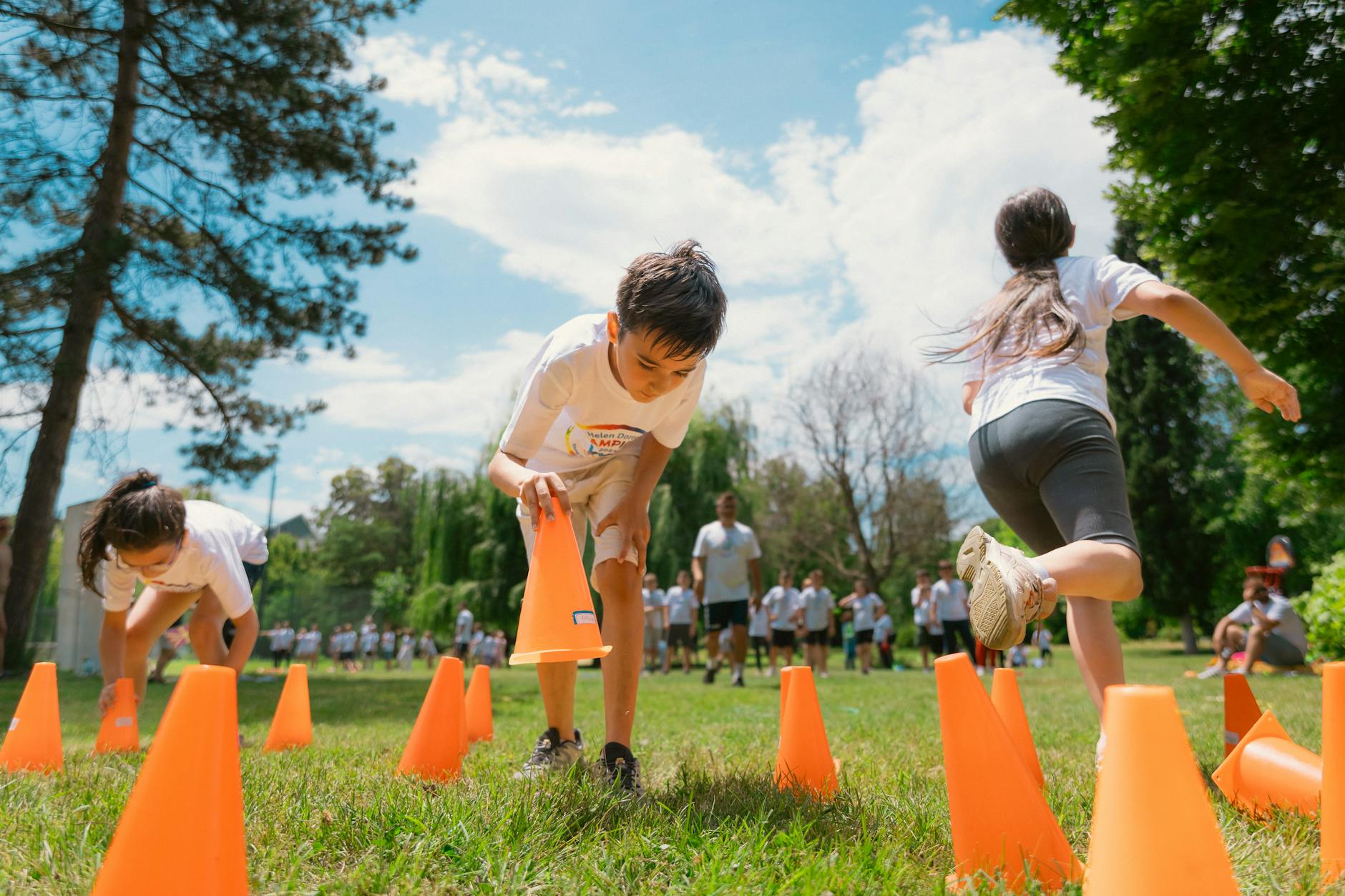 children placing obstacle course cones on grass